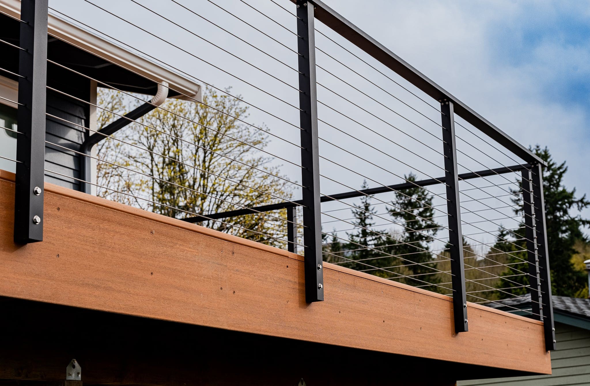 Modern cable railing on wooden deck with trees