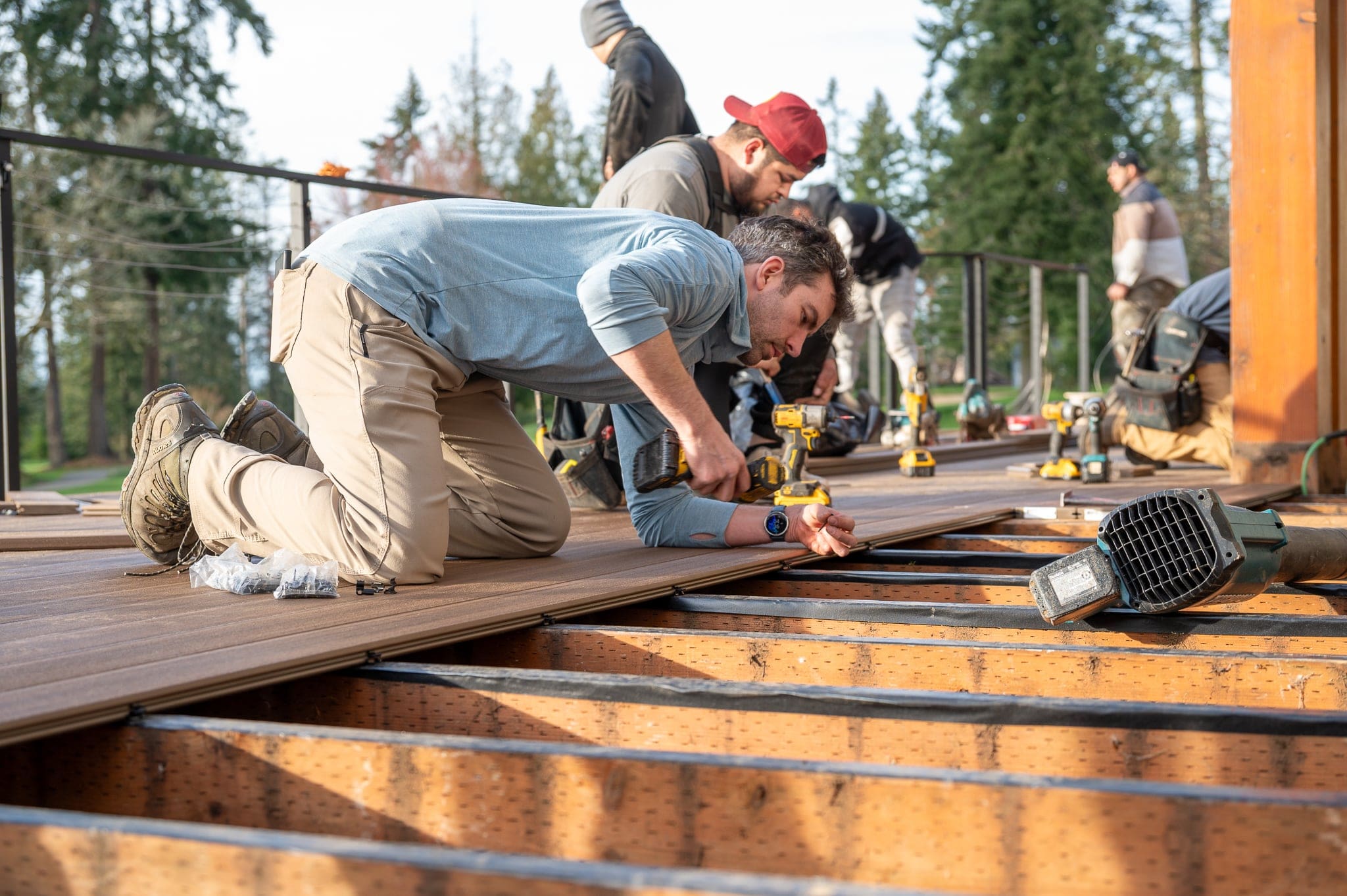 Workers building a wooden deck outside.