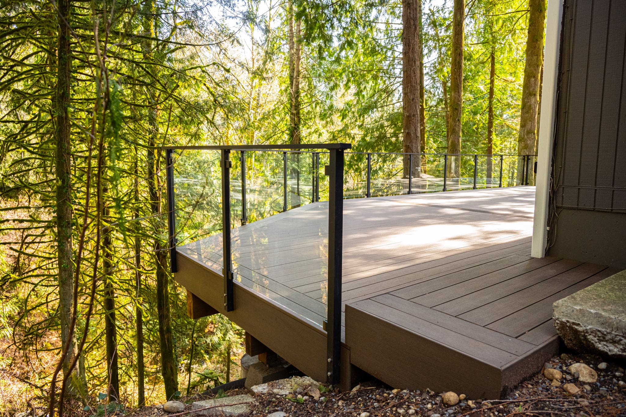 composite deck with framed glass railing overlooking forest