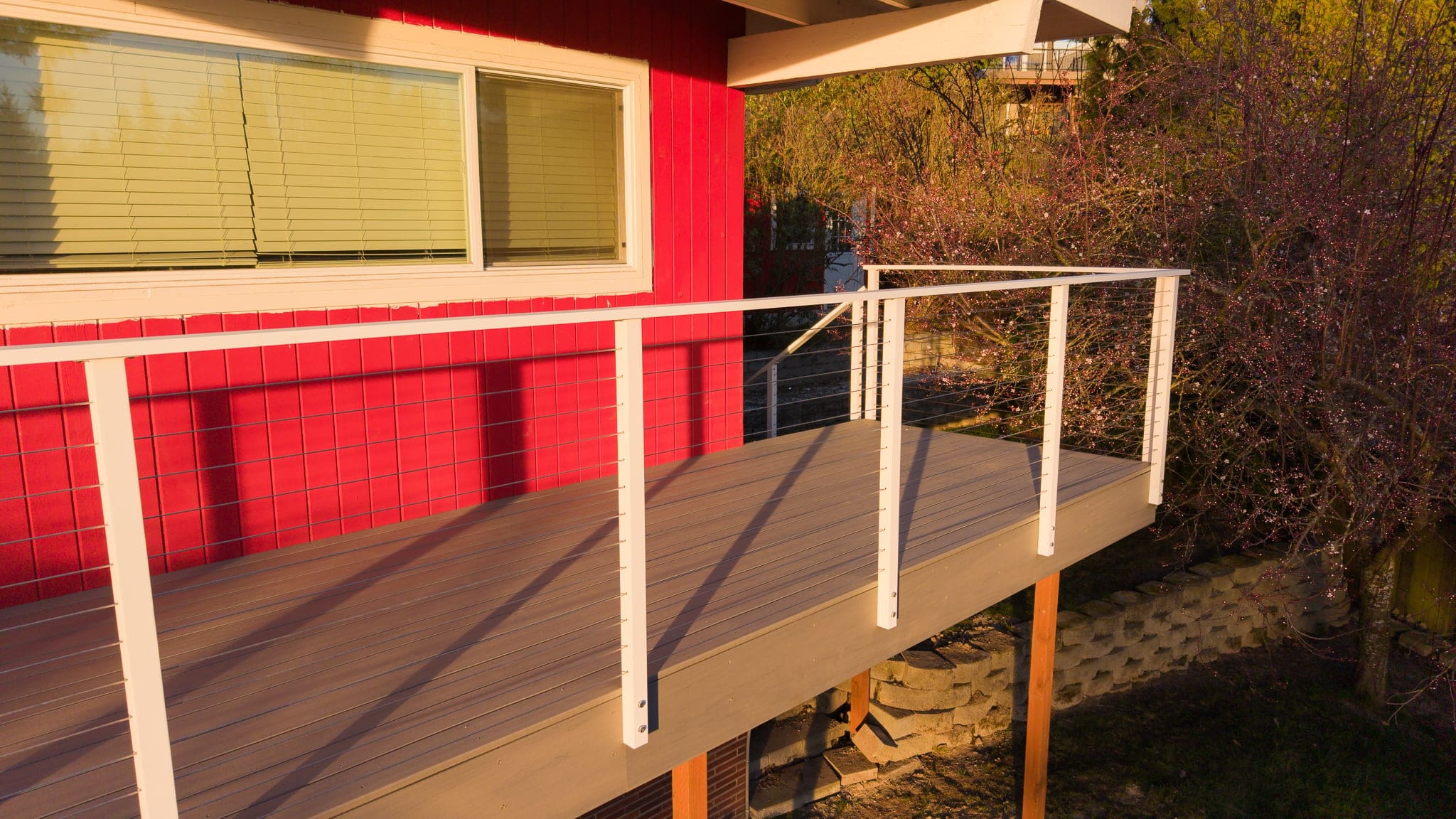 Small elevated deck with white railing on red house