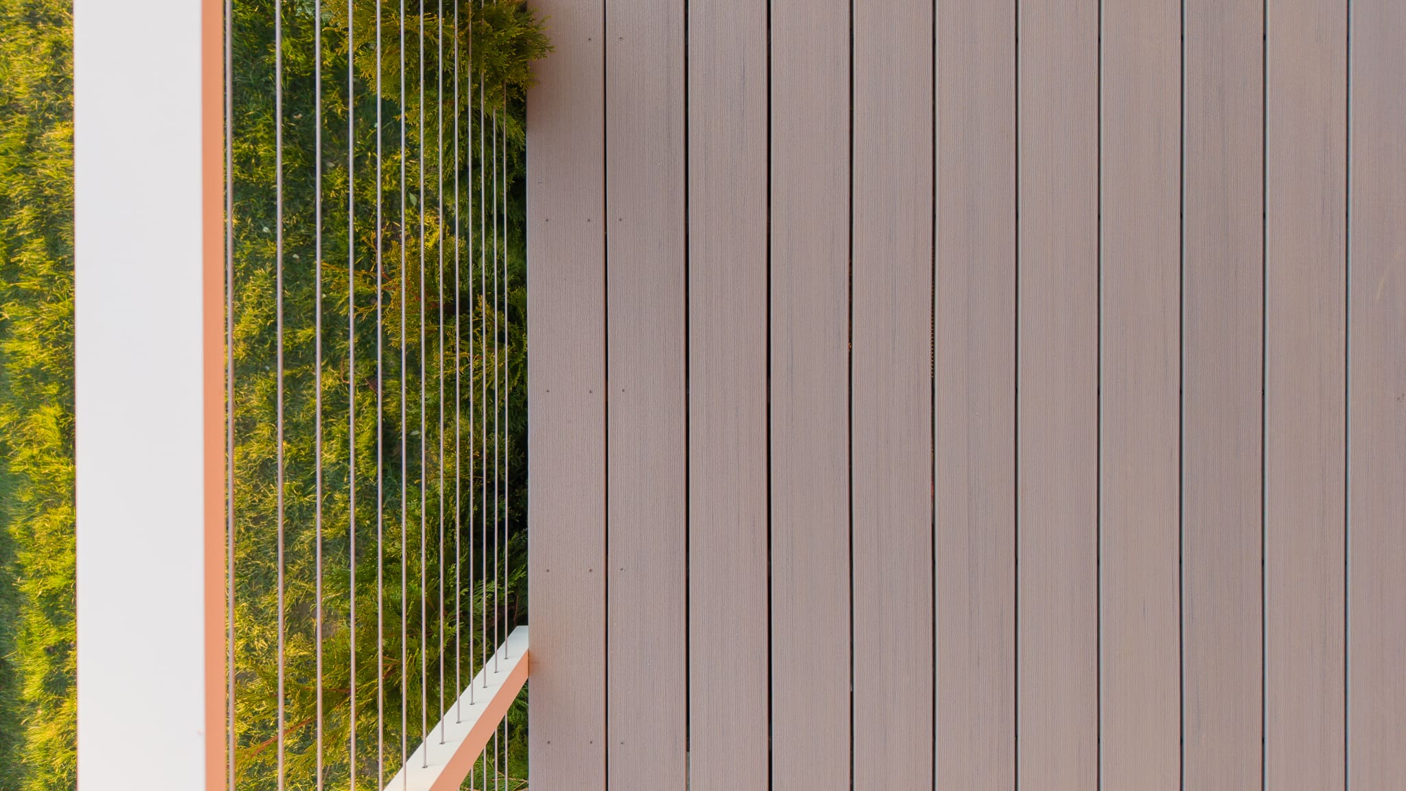 Modern wooden balcony with glass railing and greenery