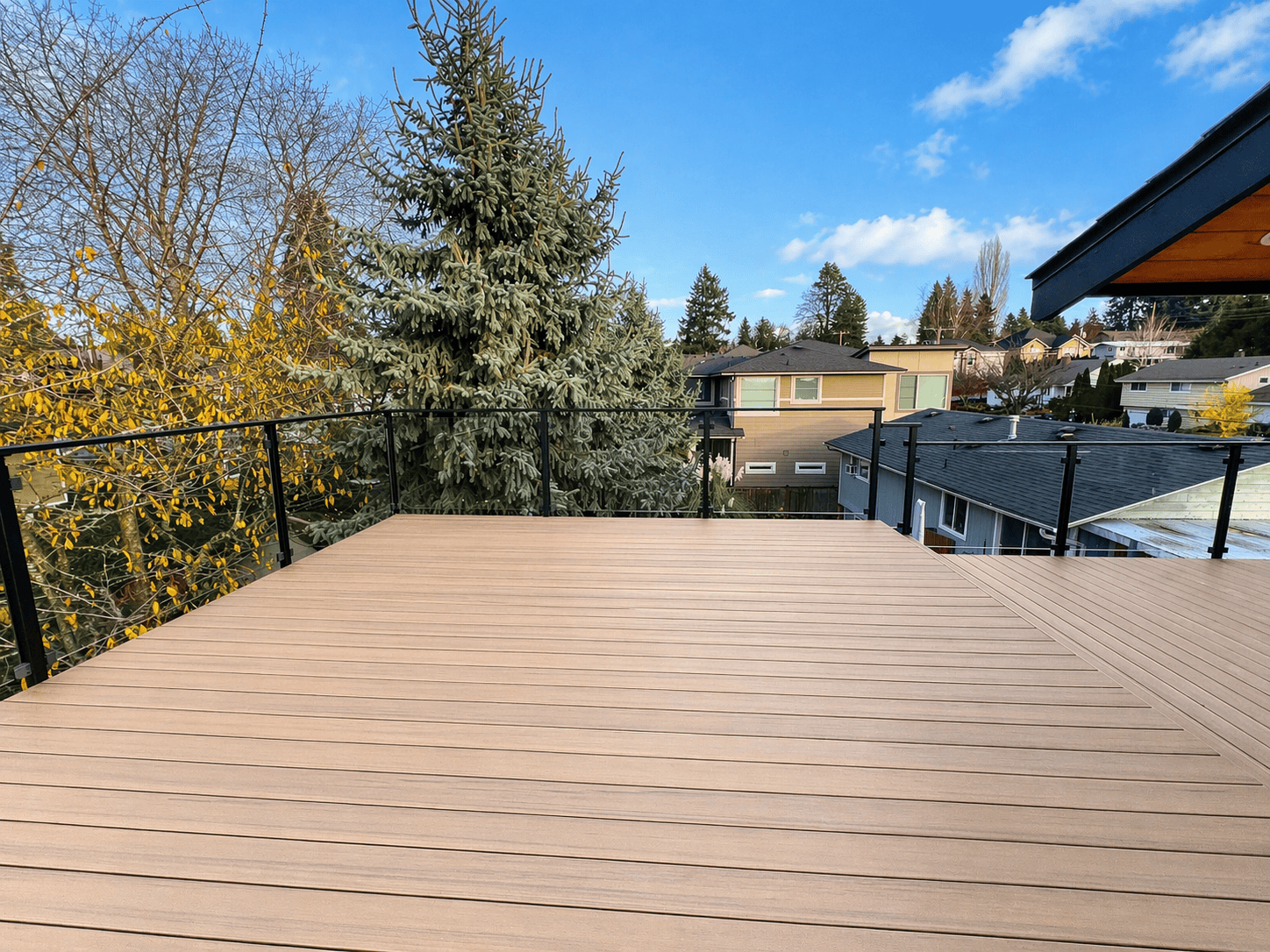 Modern backyard deck with glass railing and neighborhood view