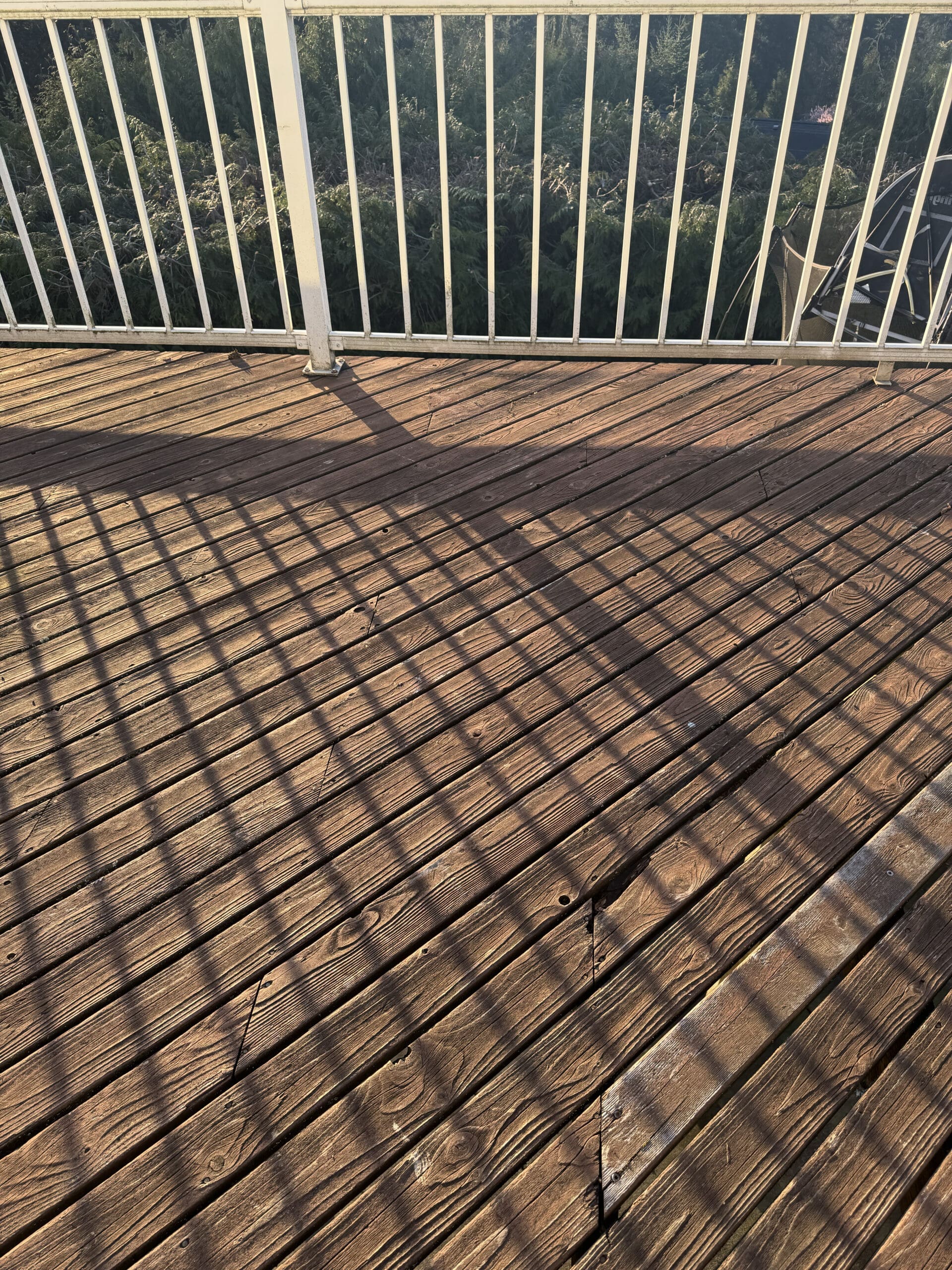 Sunlit wooden deck with white railing shadows