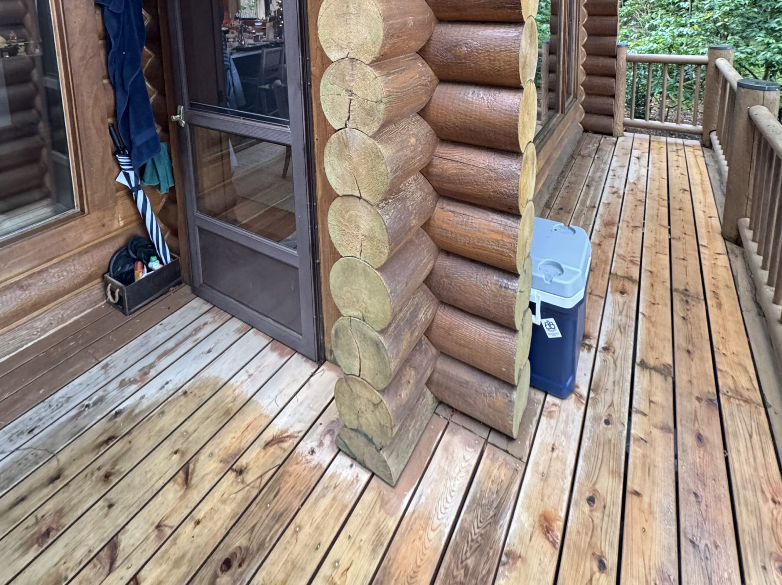 Log cabin porch with wooden deck and cooler