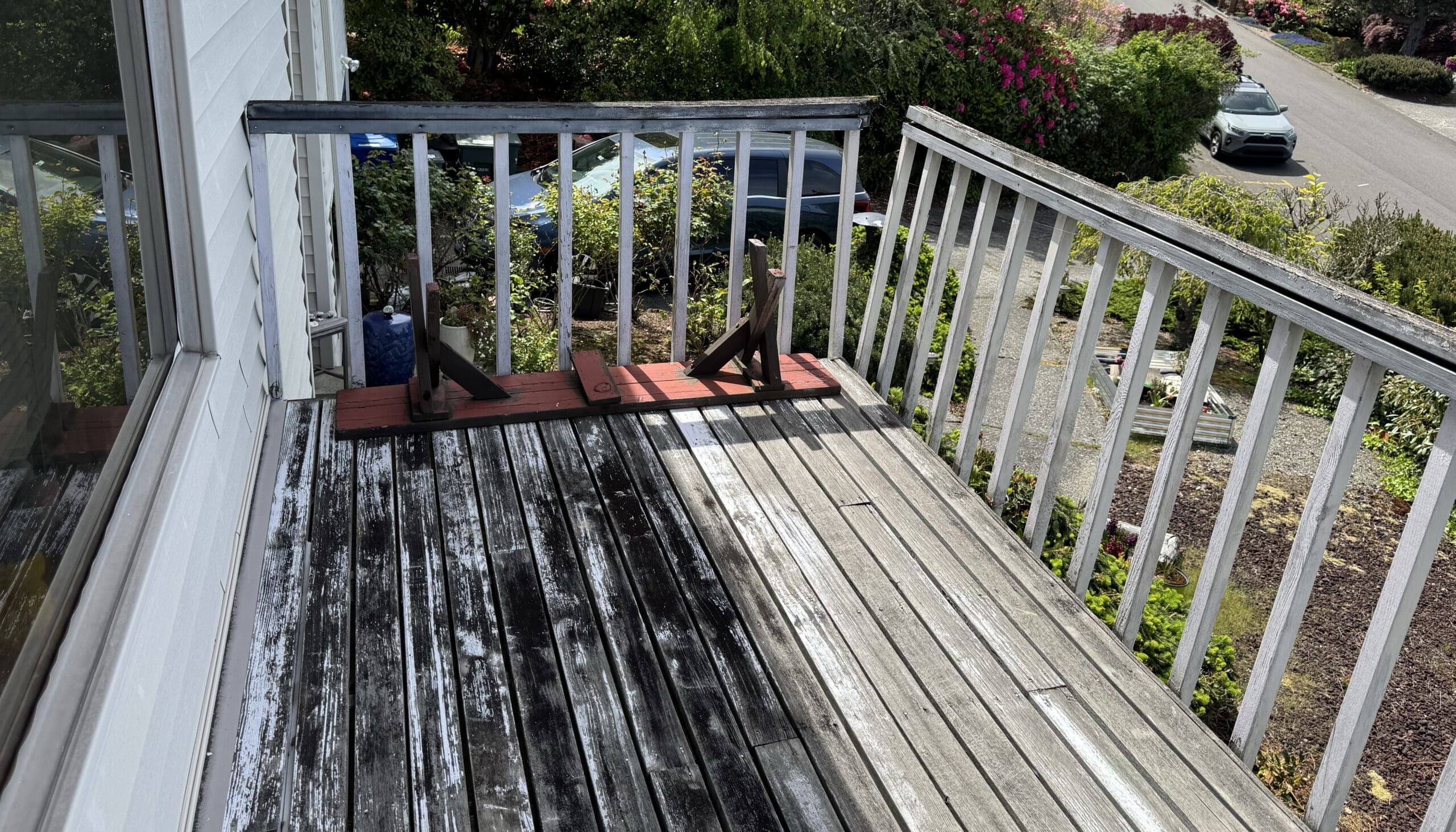 Weathered wooden balcony with partially cleaned deck boards